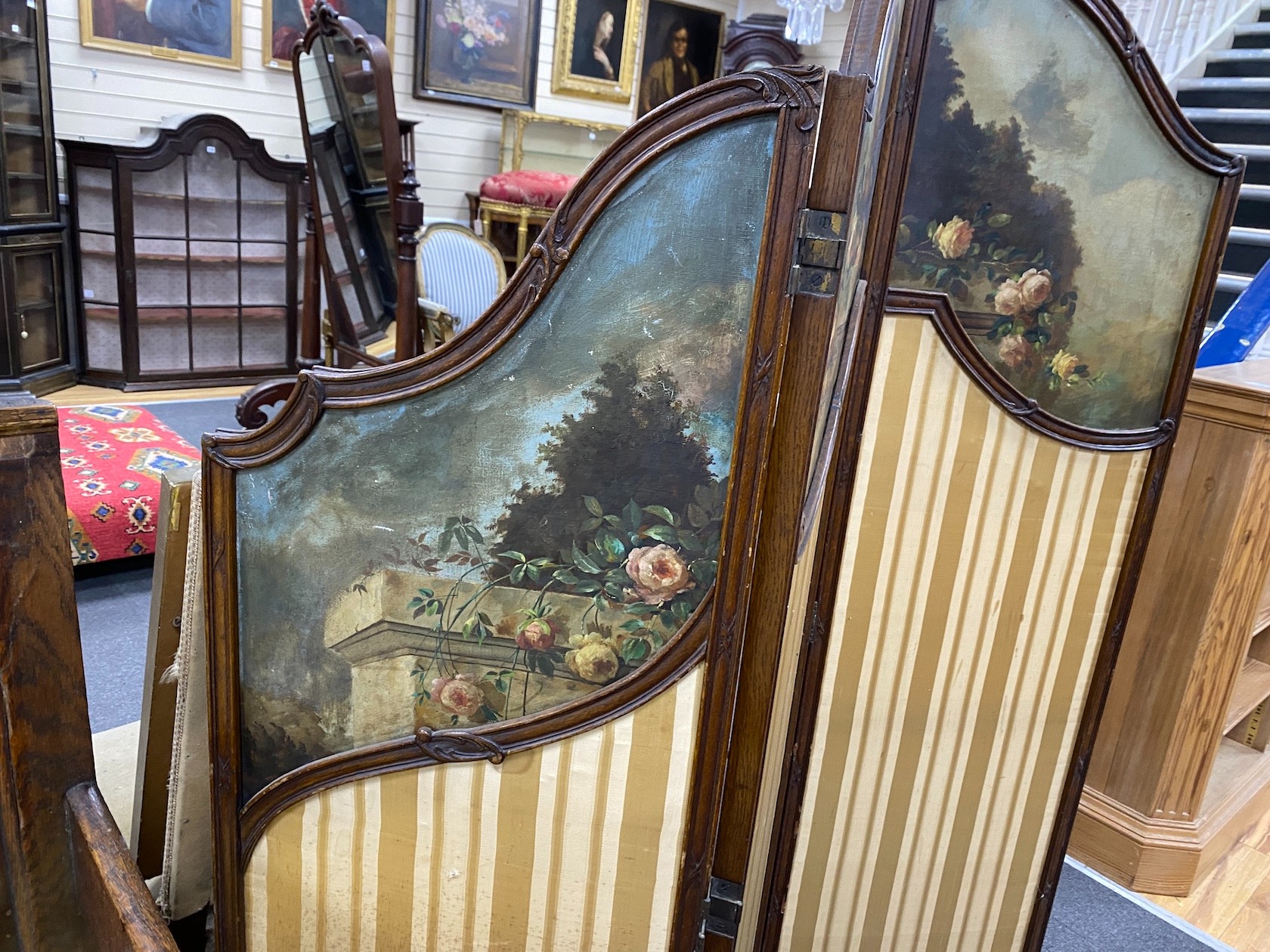 An early 20th century oak three fold screen, painted oil on canvas panels and stretched silk, height 154cm